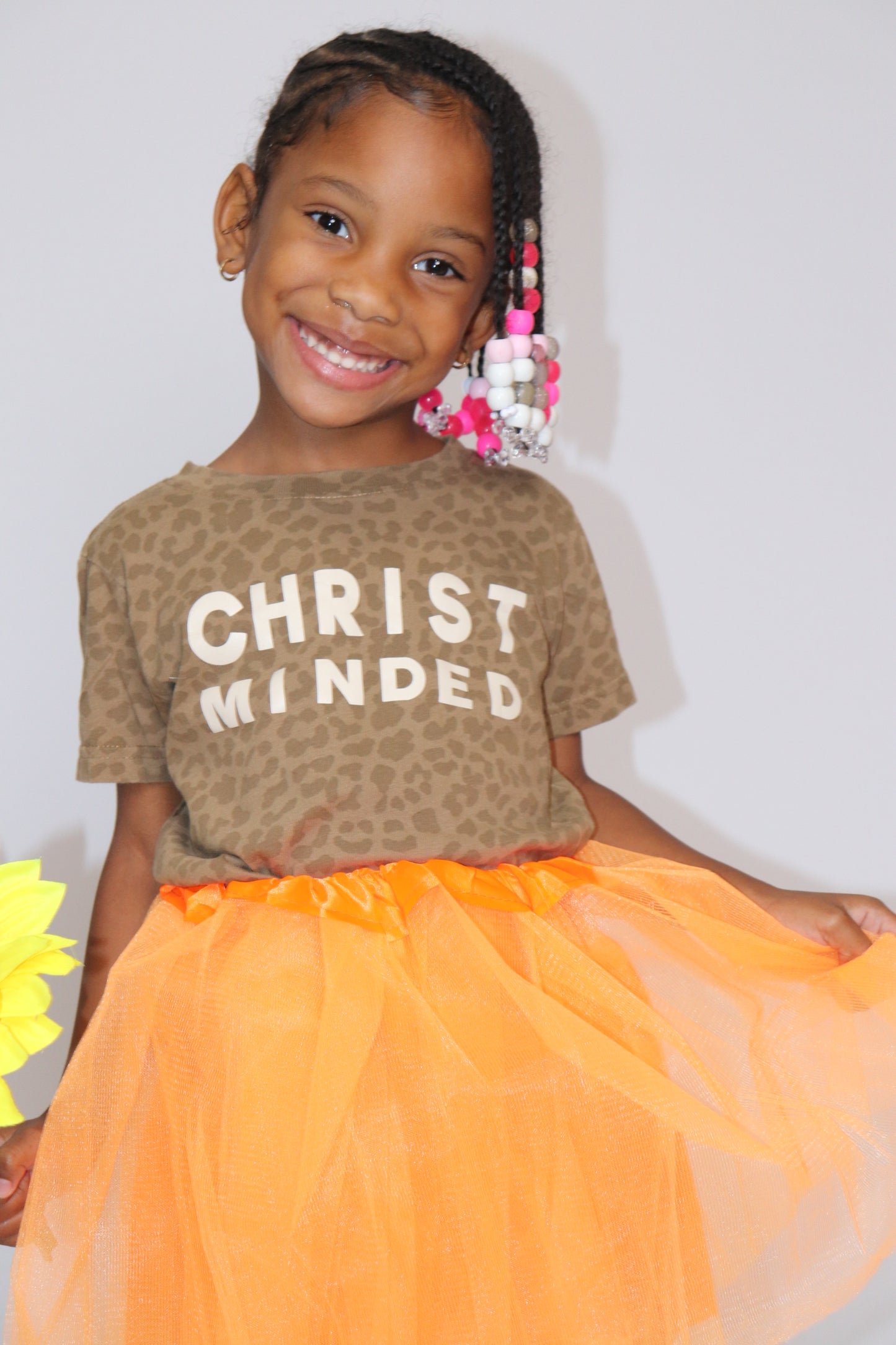 young girl smiling wearing leopard print christ minded t-shirt with orange tutu