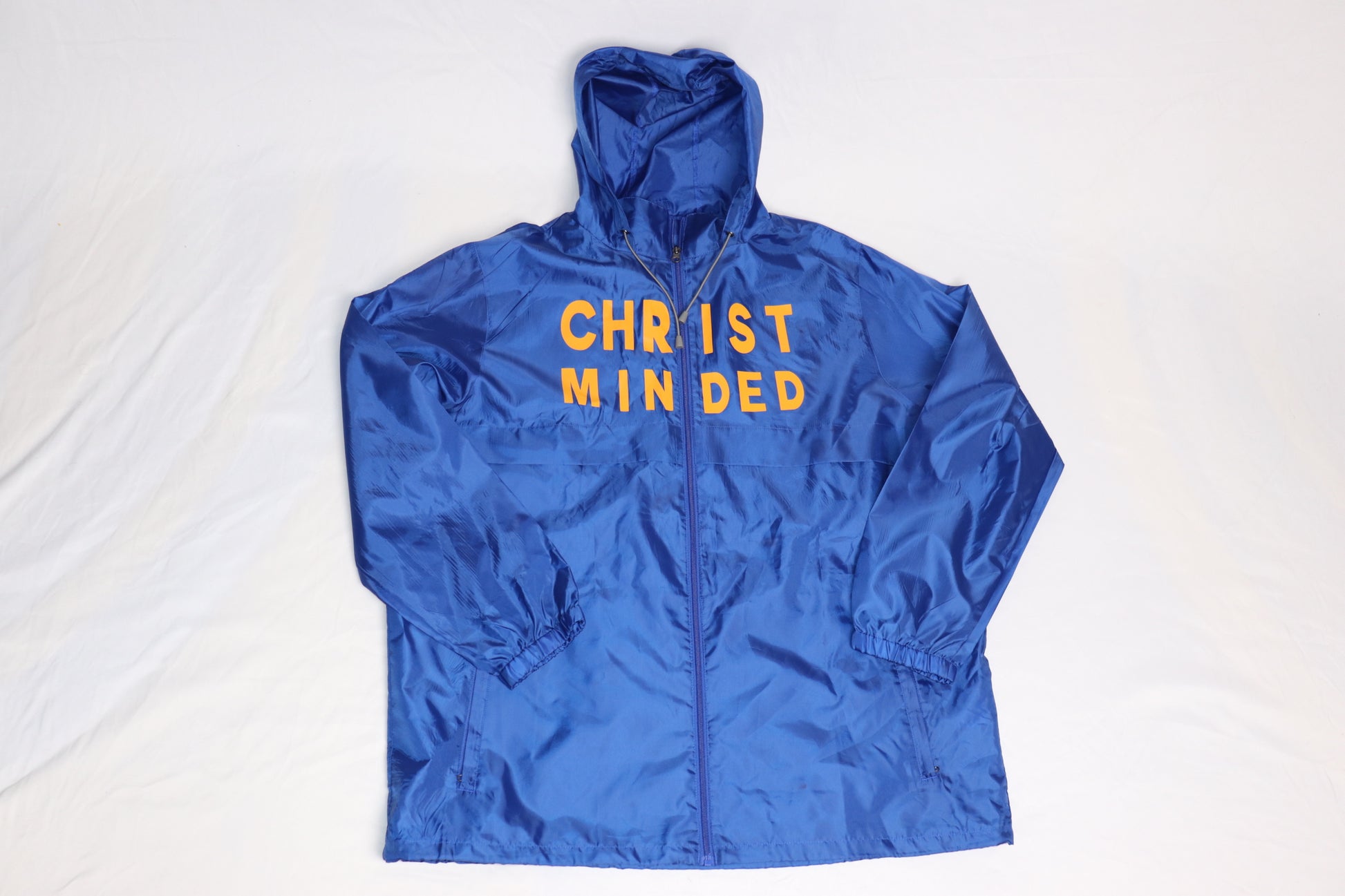 Front view of royal blue Christian windbreaker jacket with yellow text reading “CHRIST MINDED” across the chest