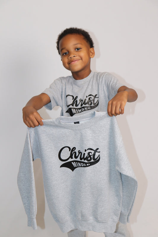 Boy holding a matching gray Christ Minded sweatshirt while wearing the same logo t-shirt