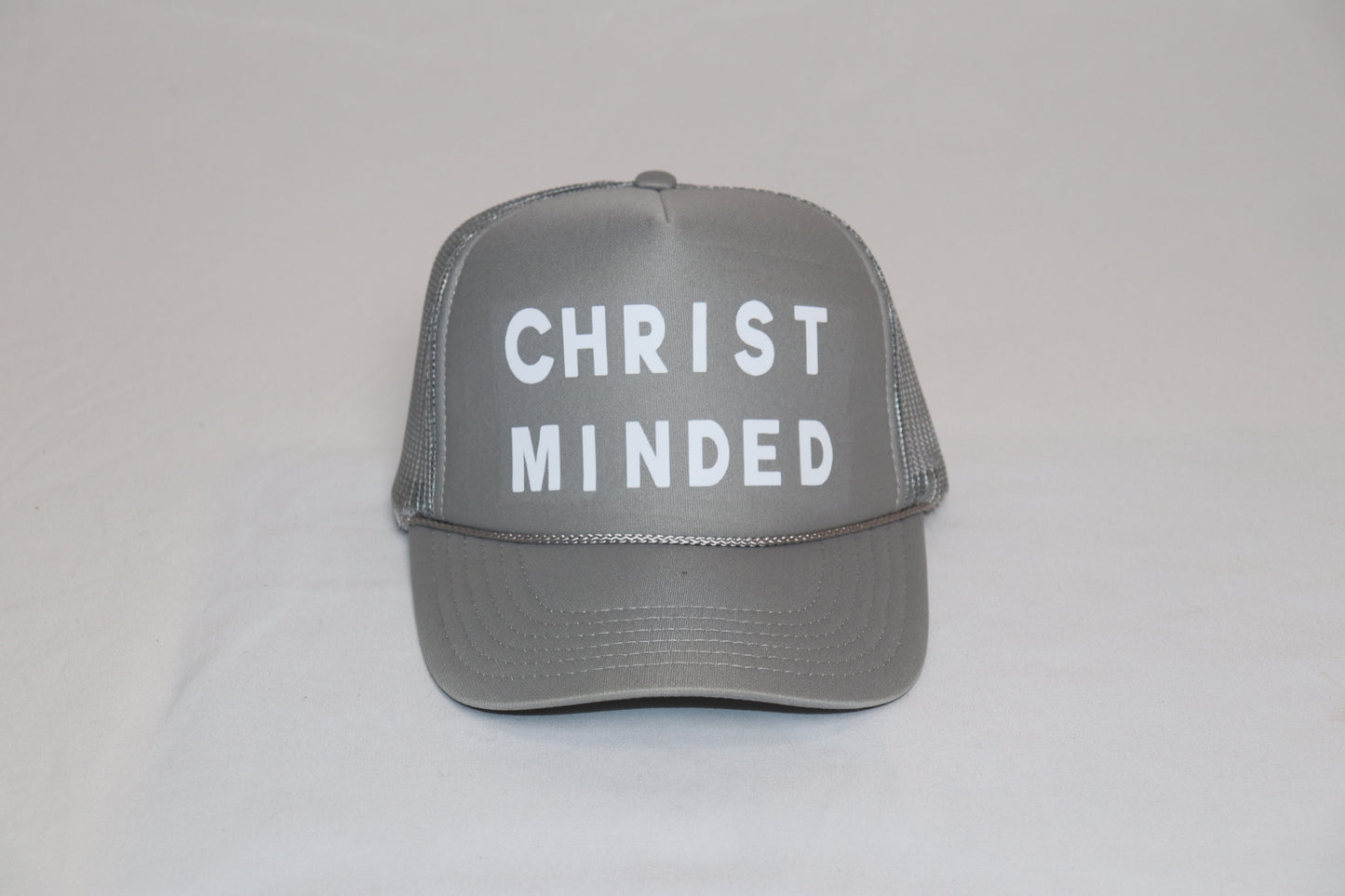 Grey Christian trucker hat with white “Christ Minded” lettering, representing strength, faith, and steadfastness.