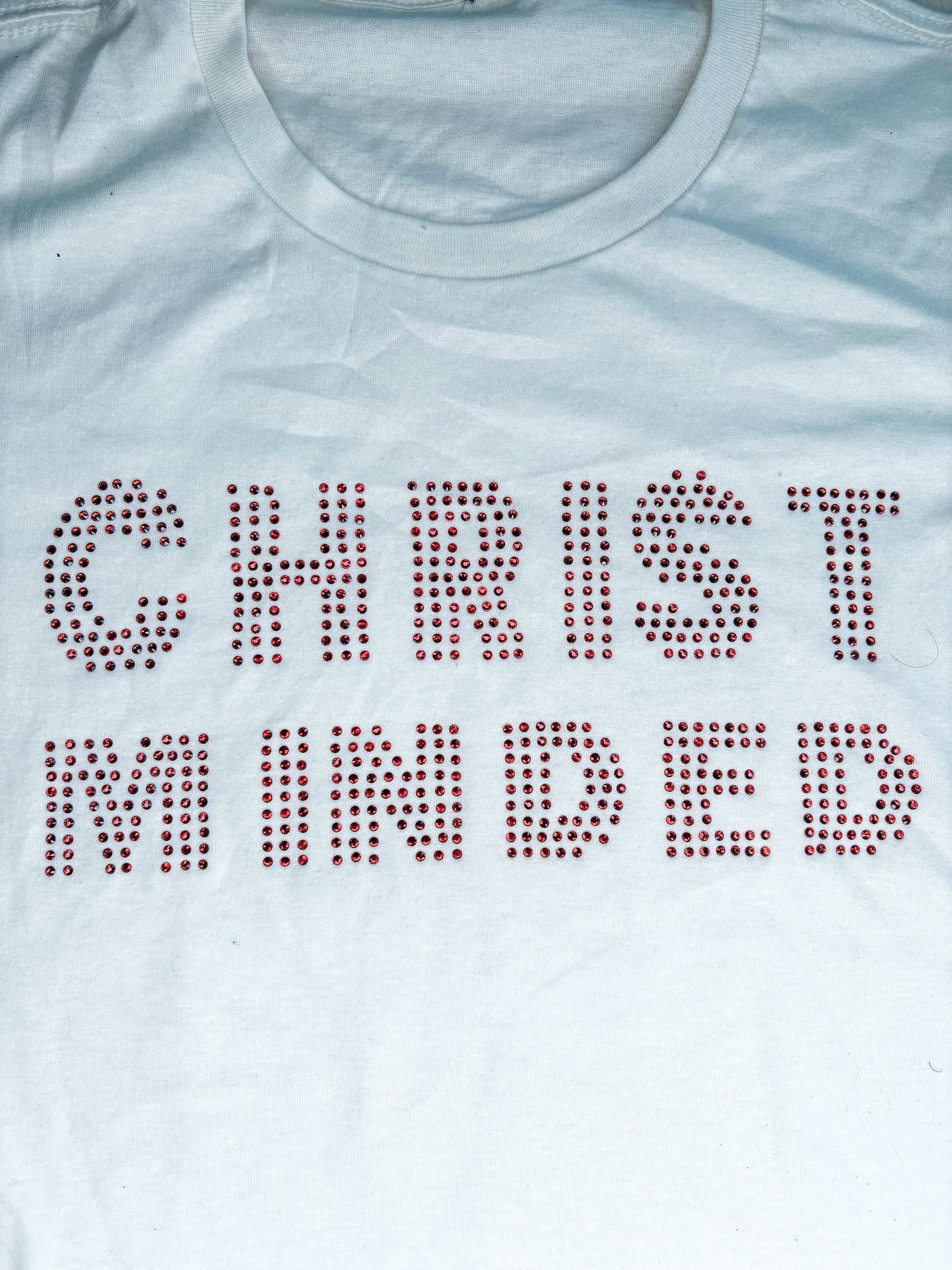 Cream t-shirt with red rhinestone lettering that reads "Christ Minded" displayed flat