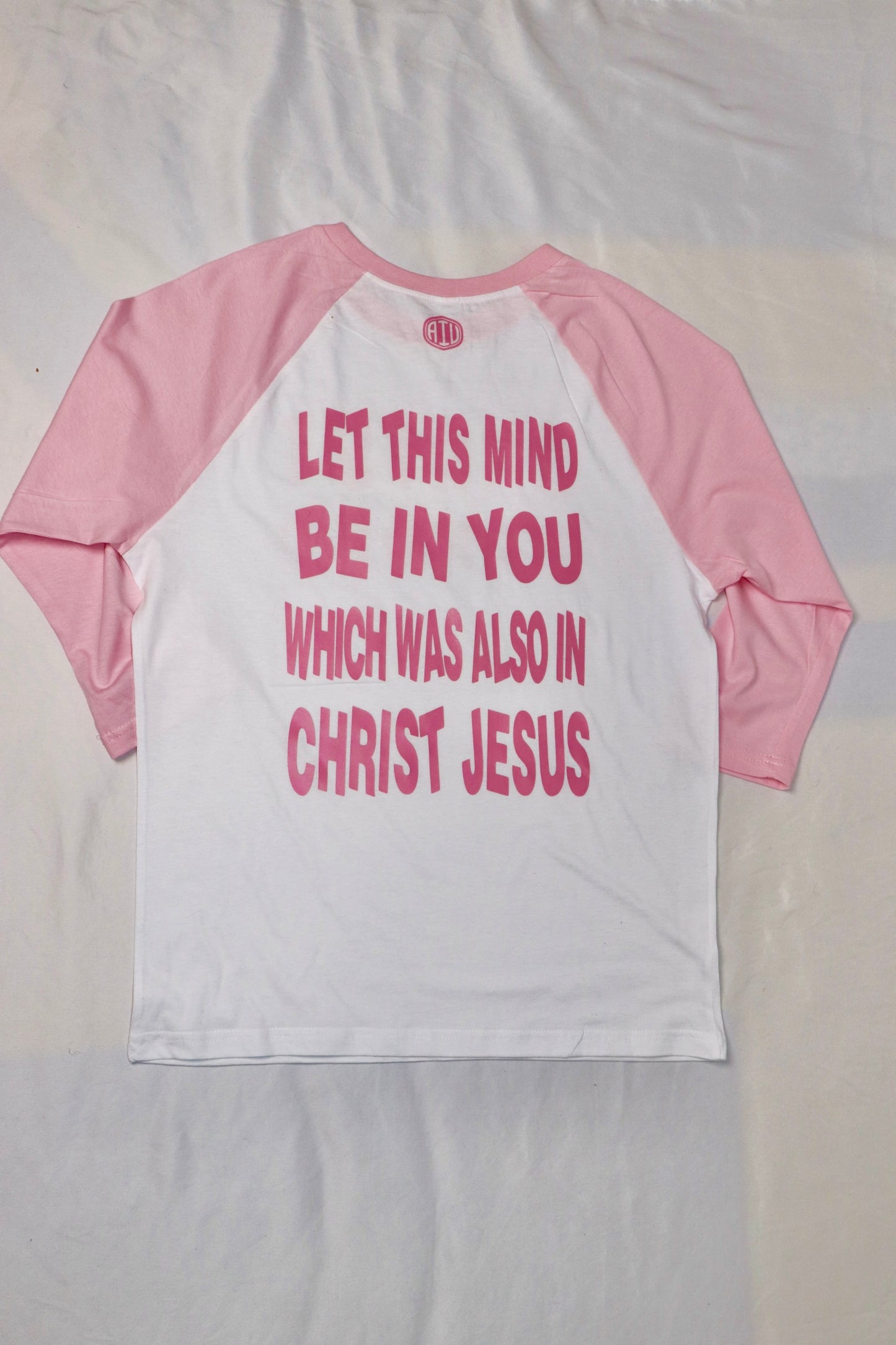 Back view of Christian baseball tee with pink sleeves and white body featuring scripture text “Let this mind be in you which was also in Christ Jesus” in bold pink letters
