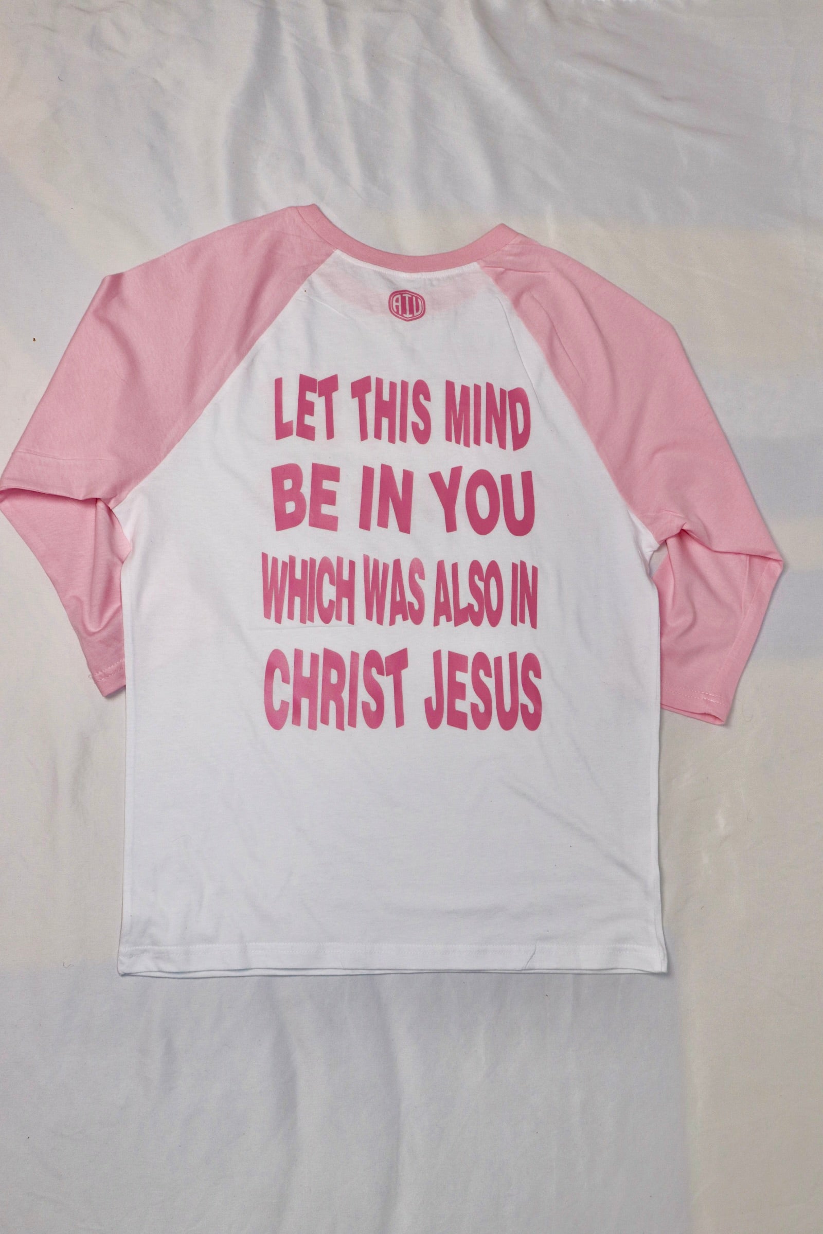 Back view of Christian baseball tee with pink sleeves and white body featuring scripture text “Let this mind be in you which was also in Christ Jesus” in bold pink letters