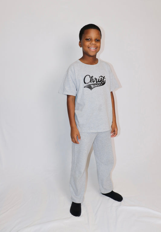 Smiling boy wearing a gray Christ Minded t-shirt and matching pants, representing a comfortable faith-based outfit for kids