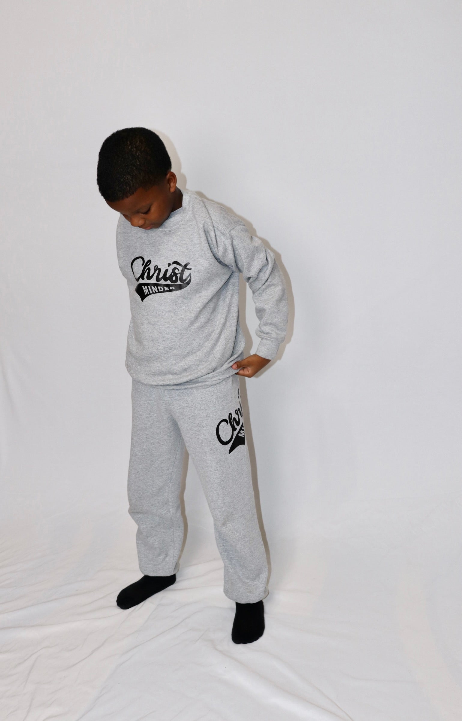 Boy wearing a gray Christ Minded sweatshirt and matching sweatpants with black lettering