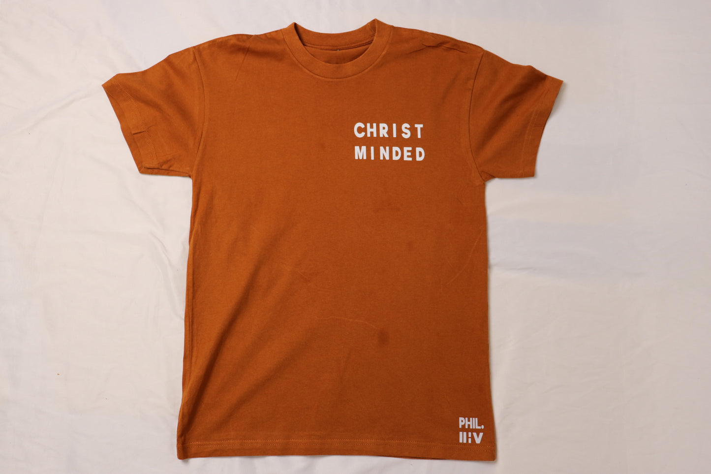Christ Minded burnt clay unisex t-shirt with white text on front featuring minimalist faith-based design