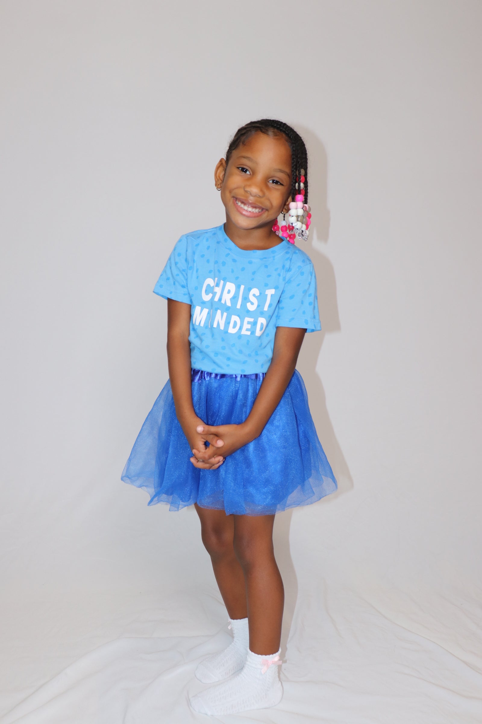 Smiling girl wearing a blue Christ Minded t-shirt with matching blue tutu, showcasing faith-based children’s fashion