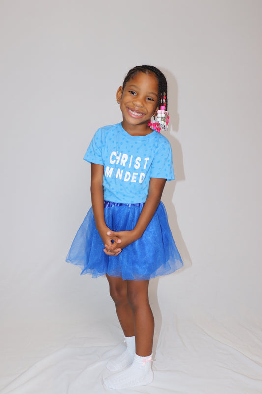 Smiling girl wearing a blue Christ Minded t-shirt with matching blue tutu, showcasing faith-based children’s fashion