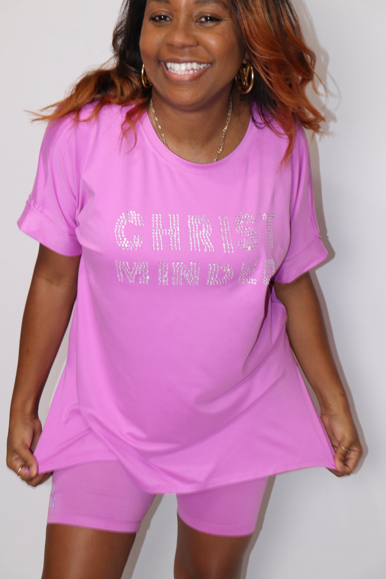 Woman smiling wearing a pink “Christ Minded” rhinestone shirt and matching shorts set