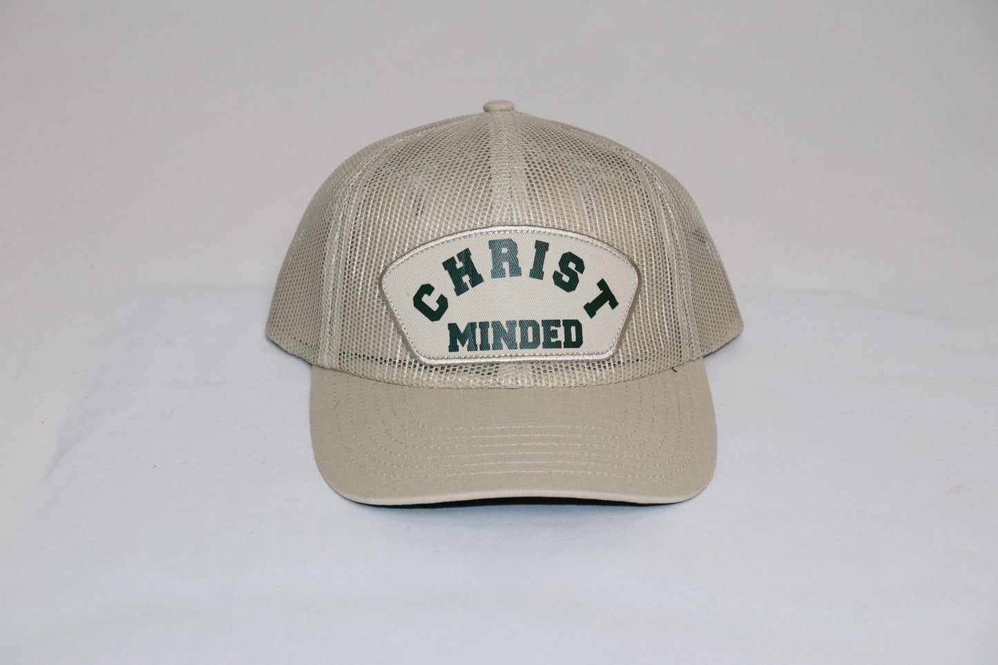Christ Minded Sandstone Faith Cap with beige mesh and green embroidered patch reading “Christ Minded,” a vintage Christian trucker hat inspired by Philippians 2:5.