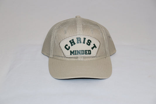 Christ Minded Sandstone Faith Cap with beige mesh and green embroidered patch reading “Christ Minded,” a vintage Christian trucker hat inspired by Philippians 2:5.