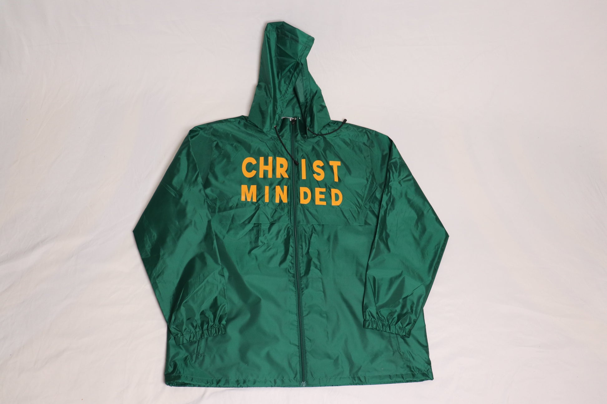 Front view of green Christian zip-up hooded jacket with bold yellow text reading “CHRIST MINDED” across the chest