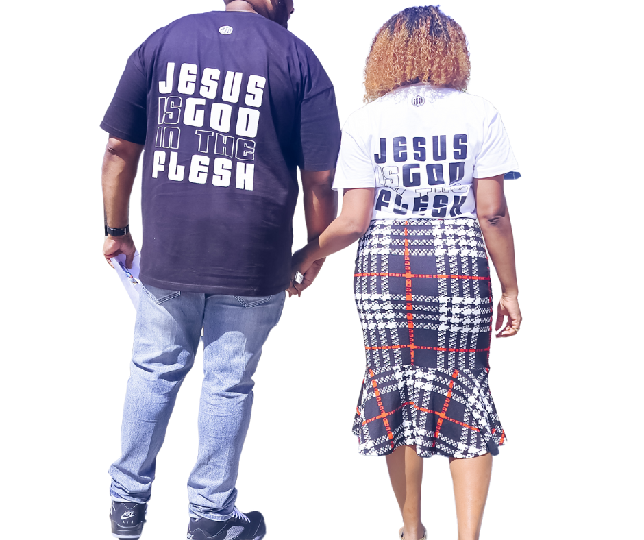 Couple walking hand in hand wearing matching shirts that say “Jesus Is God in the Flesh” — man in black tee, woman in white tee paired with a plaid skirt.